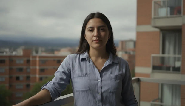 Vitamina D3 para qué sirve: mujer tomando sol en los antebrazos desde el balcón de un apartamento en una mañana nublada de Bogotá
